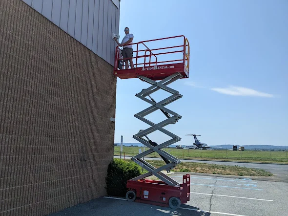 Installer using an elevated work platform beside a commercial building